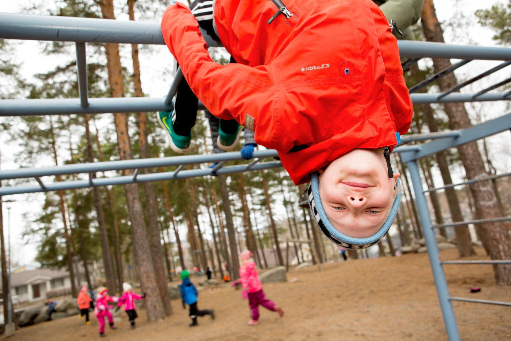 Lapsi roikkuu leikkikentän kiipeilytelineessä.