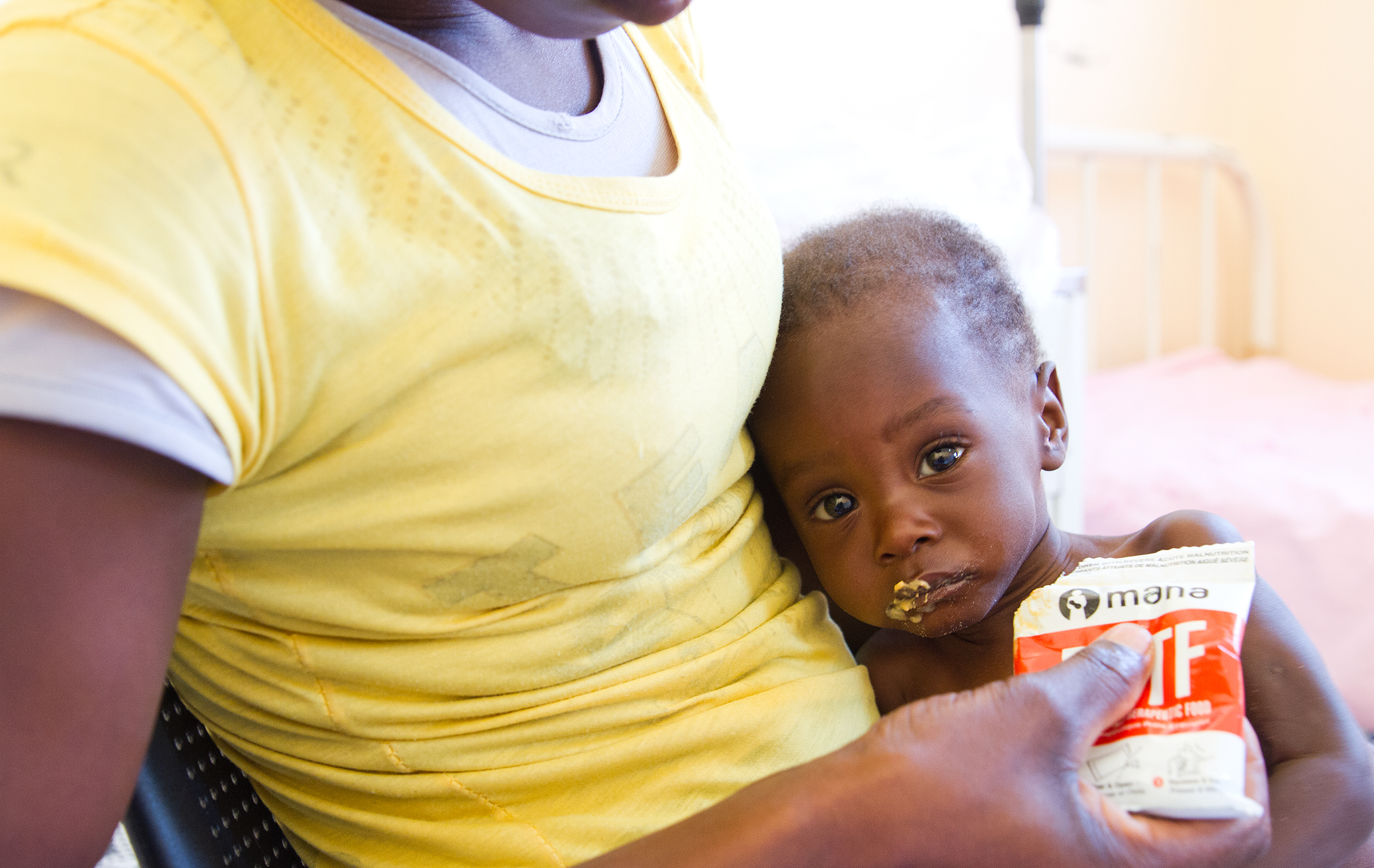 Pieni Marcelino äidin sylissä ja pussi maapähkinätahnaa. © UNICEF/UN023908/Clark