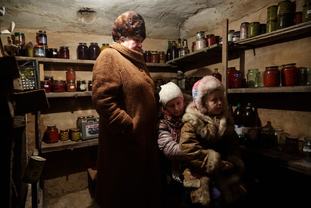  Itä-Ukrainassa sisarukset Diana (keskellä) ja Sasha piiloutuvat pommitusten aikana isoäitinsä Ninan kanssa talon kellariin. Kuva: © UNICEF/UN053113/Zmey