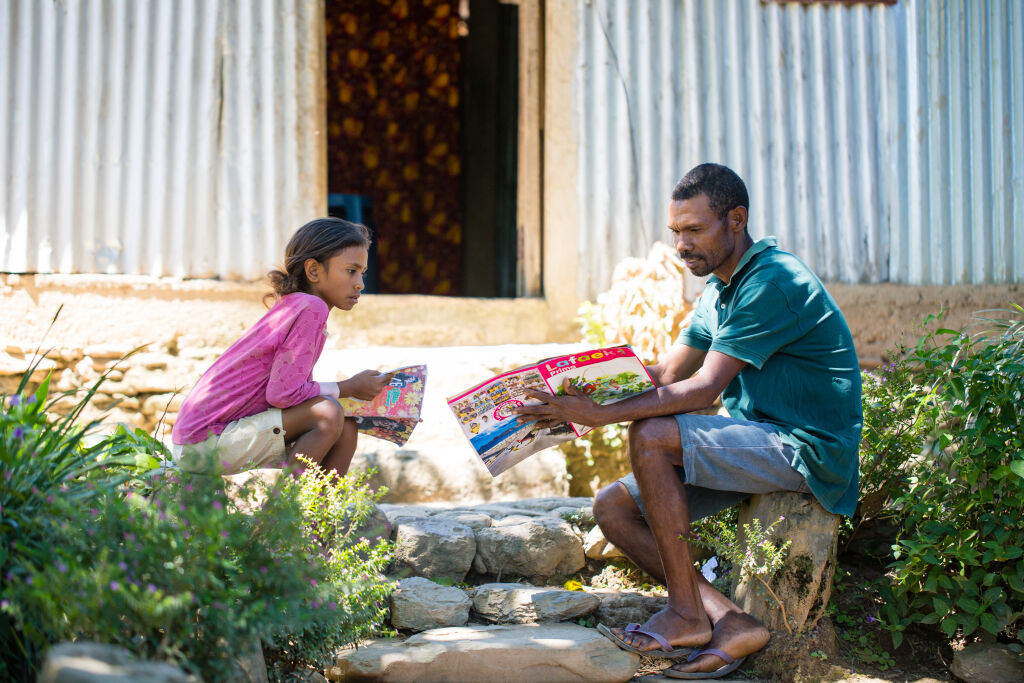 Cristina Elena Mendonca, 10 vuotta, saa apua koulutehtäviinsä isältään Joaquimilta Fahiriassa, Itä-Timorissa. Kuva: © UNICEF/UNI329961/Soares.