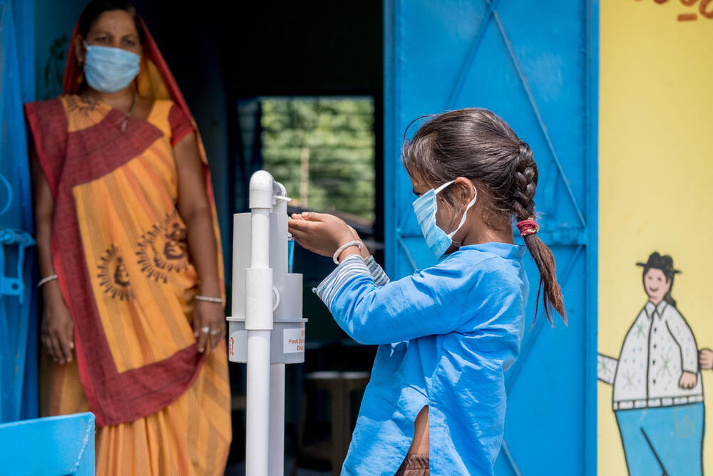 6-vuotias Paya Patel käyttää jalkapedaalilla toimivaa käsidesin annostelijaa Intian Gujaratissa. © UNICEF/UNI338883/Panjwani