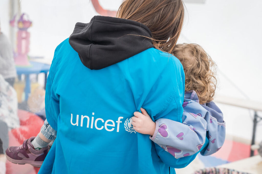 Lapsi UNICEFin työntekijän sylissä.