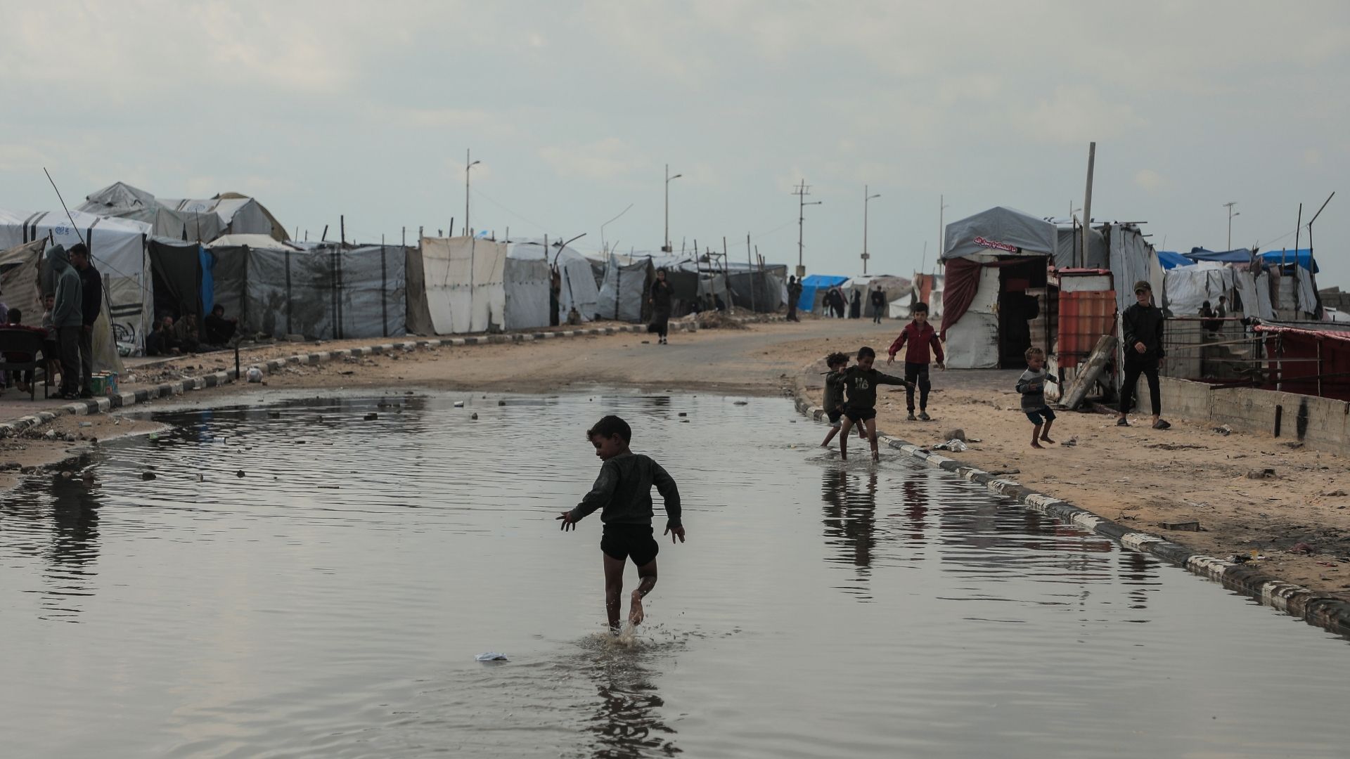 Lapsi juoksee vesilammikossa Gazassa.