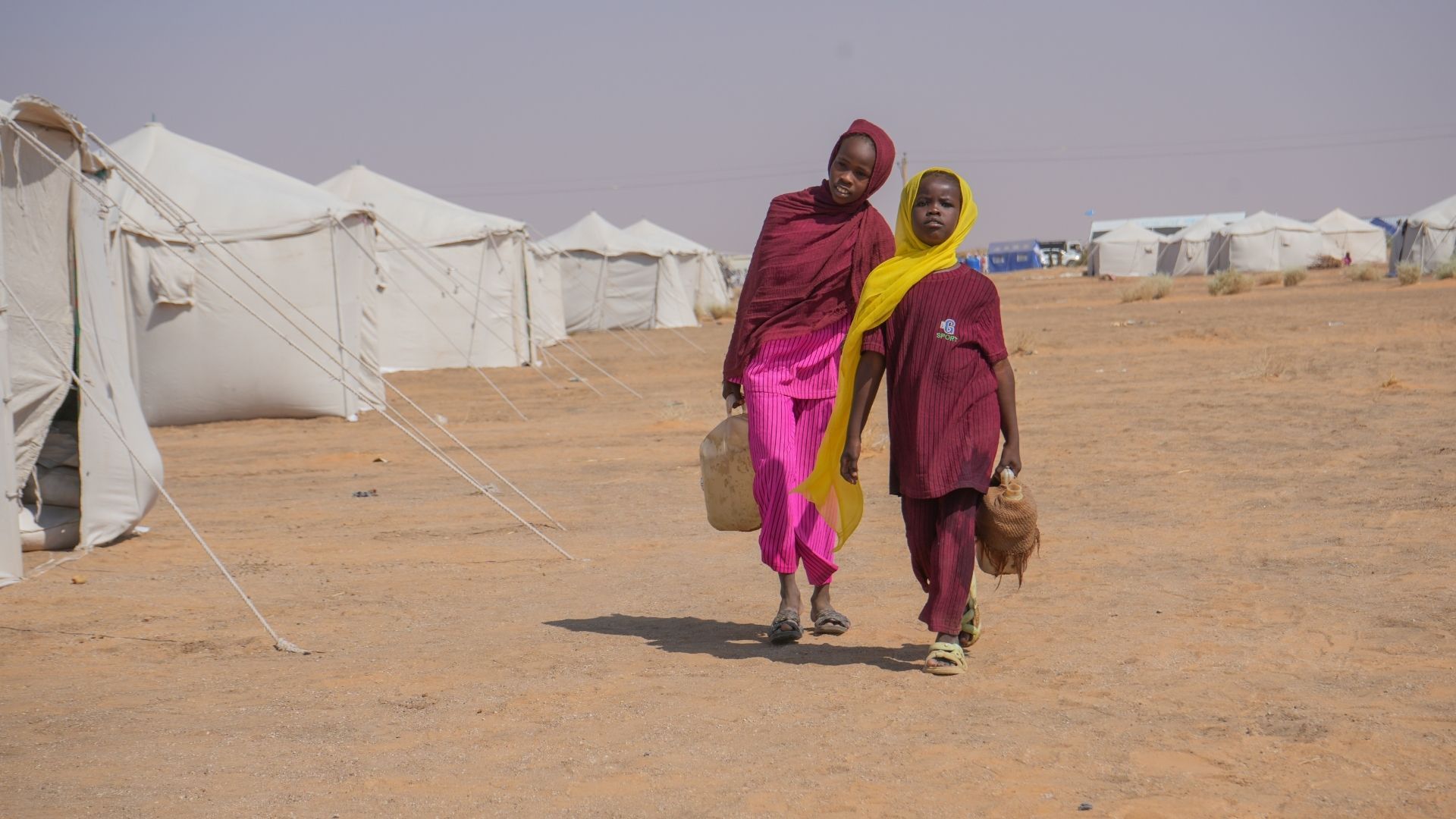 Sudanilaiset tytöt kantavat vettä pakolaisleirillä.