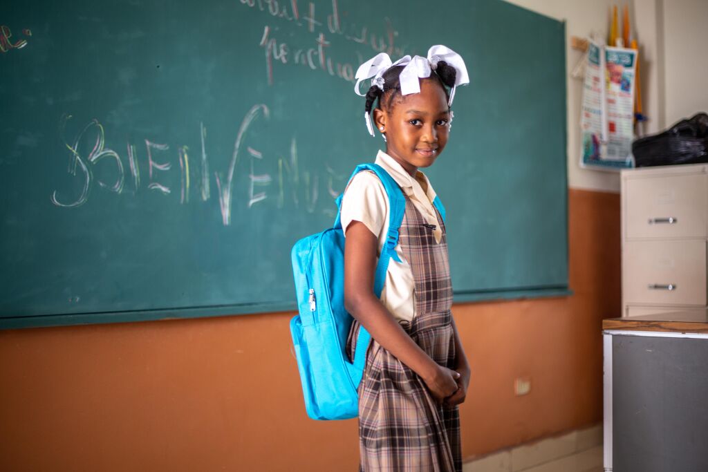 Lapsi luokan edessä UNICEF-reppu selässään.