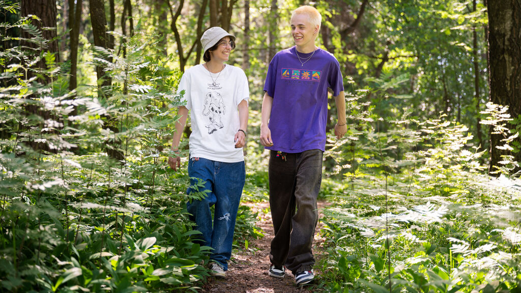 Kaksi teini-ikäistä lasta kävelyllä metsässä.