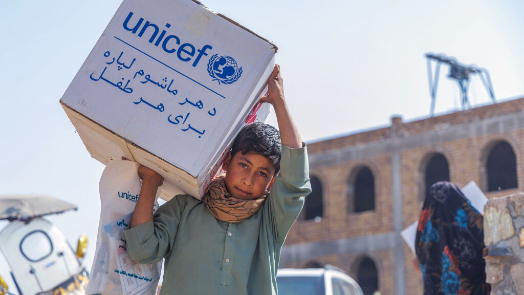 Poika kantaa laatikollista UNICEFin avustustarvikkeita.
