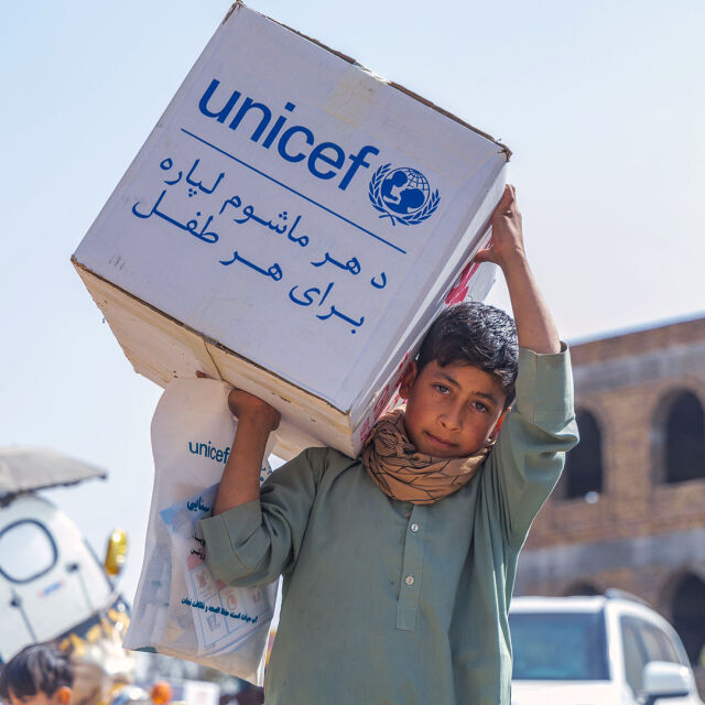 Poika kantaa laatikollista UNICEFin avustustarvikkeita.