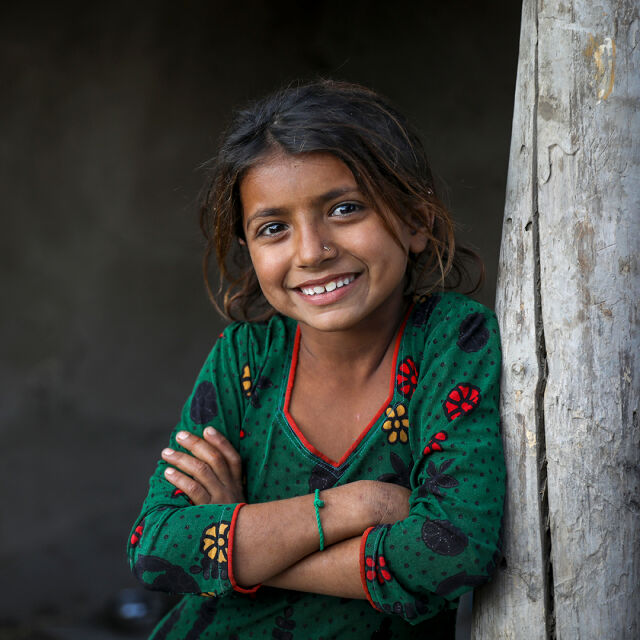 Lapsi vihreässä paidassa nojaa puuaitaan.