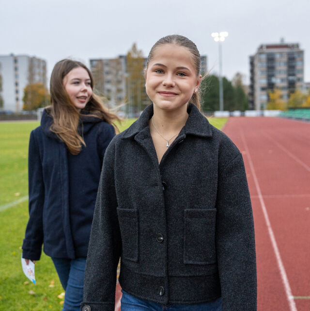 Yläkouluikäinen nuori kävelee urheilukentällä.