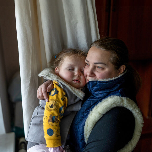 Punaiseen toppatakkiin ja siniseen tupsupipoon pukeutunut lapsi pitelee majavapehmolelua rakennuksen edessä.