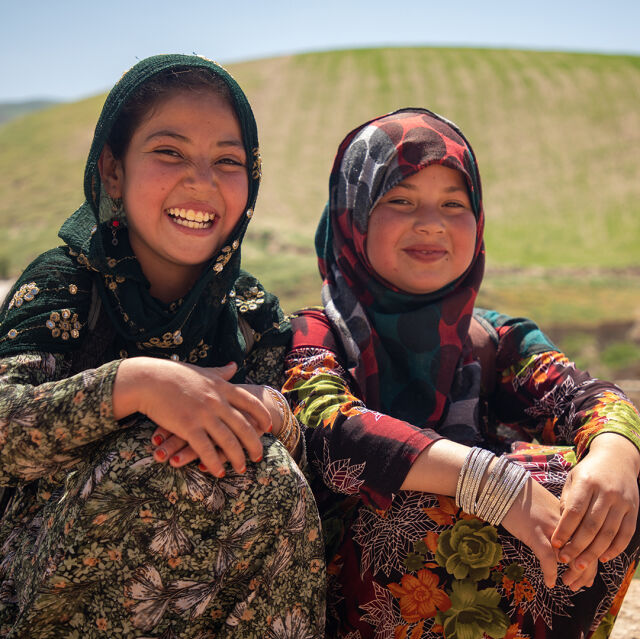 Kaksi koululaista istuu tien varressa Afganistanissa.