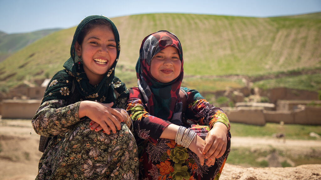 Kaksi koululaista istuu tien varressa Afganistanissa.