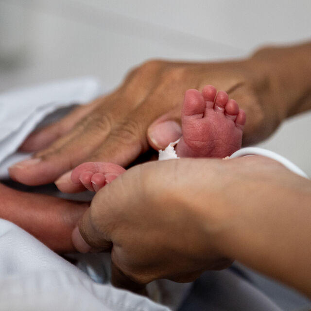 Aikuisen kädet hierovat vastasyntyneen jalkoja.