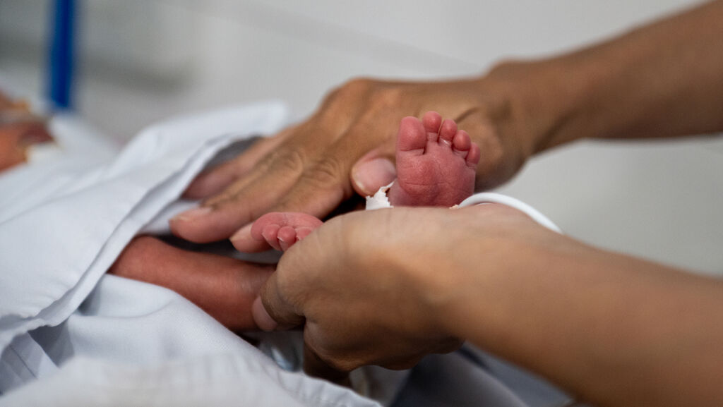 Aikuisen kädet hierovat vastasyntyneen jalkoja.