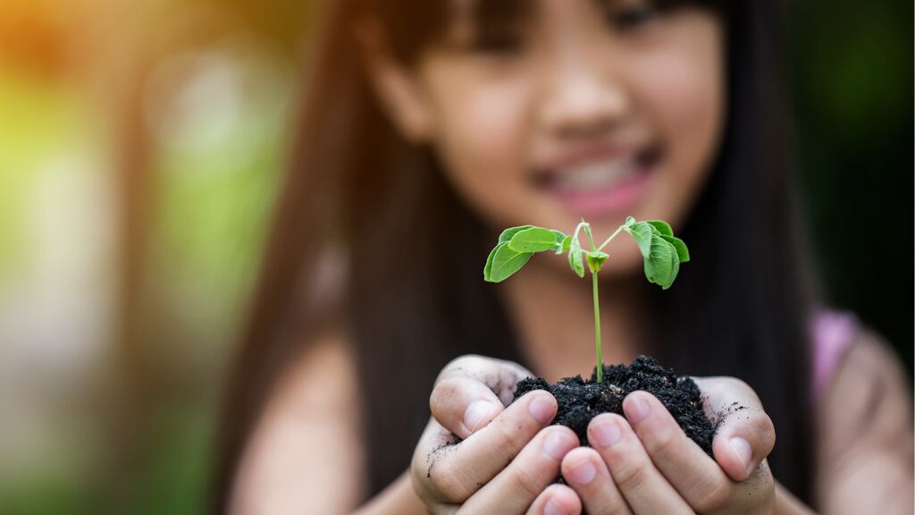 Lapsi pitelee käsisään kasvin tainta.