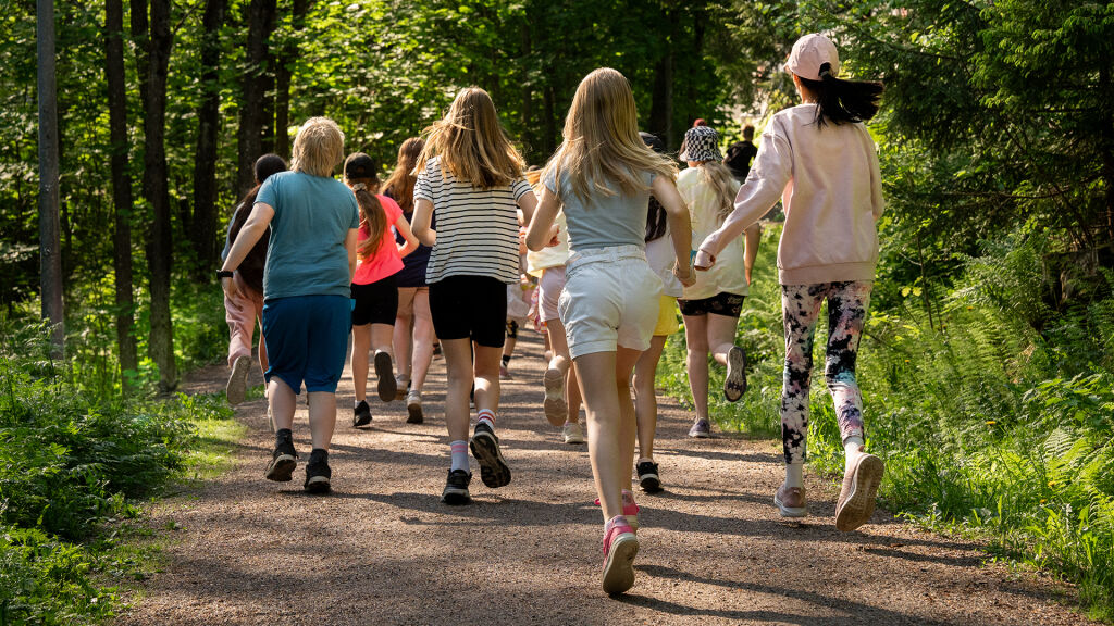 Joukko koululaisia juksee metsätiellä.