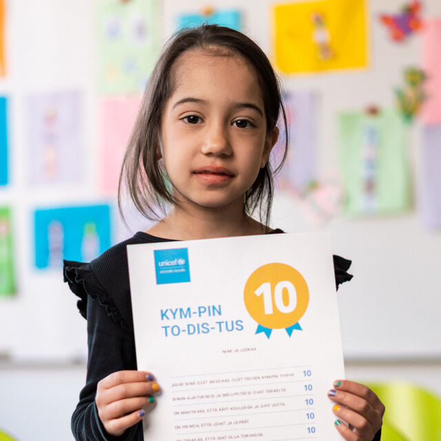 Ekaluokkalainen pitelee kädessään UNICEFin Kympin todistusta.