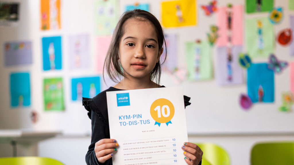 Ekaluokkalainen pitelee kädessään UNICEFin Kympin todistusta.