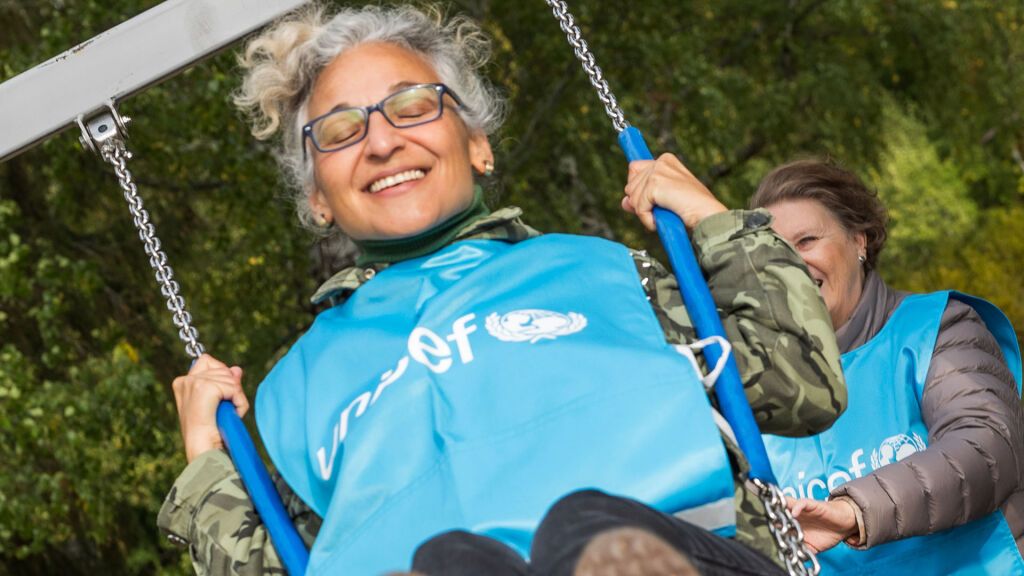 UNICEF-vapaaehtoinen keinuu sininen liivi päällään.