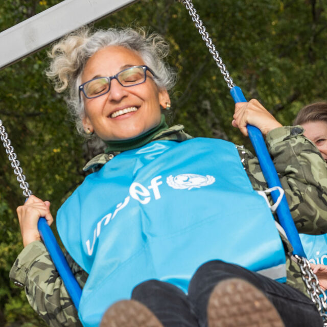 UNICEF-vapaaehtoinen keinuu sininen liivi päällään.