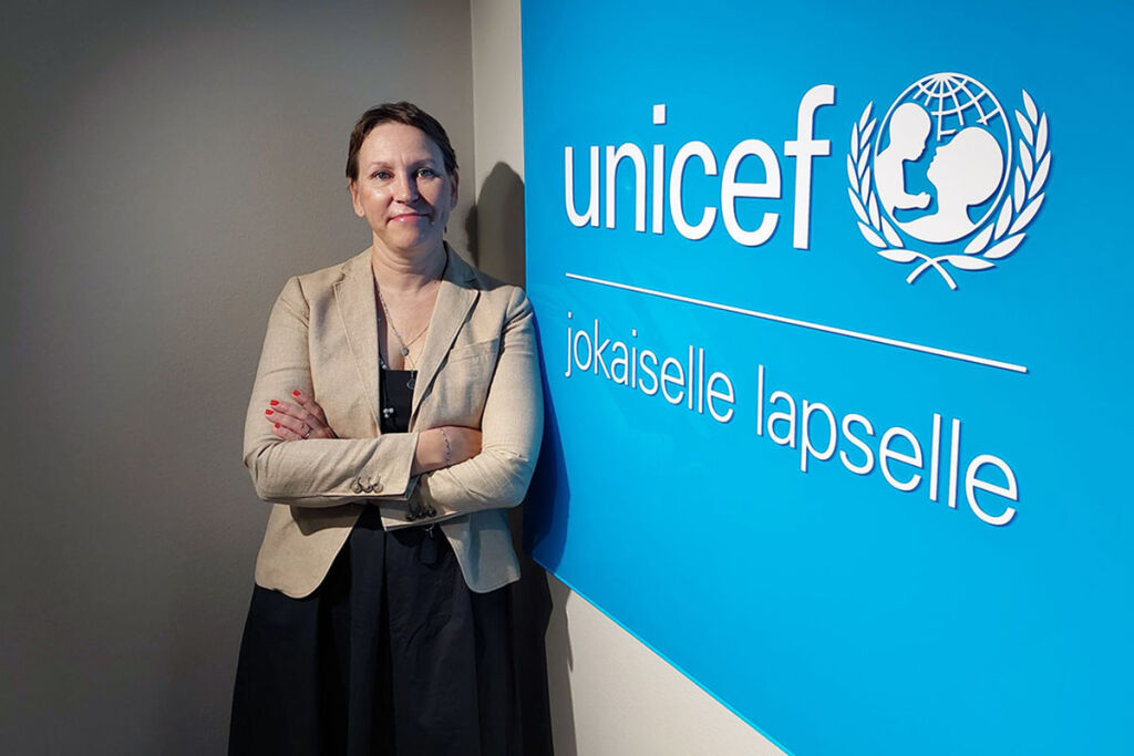 Mirkka Mattila nojaa UNICEFin logoseinään.