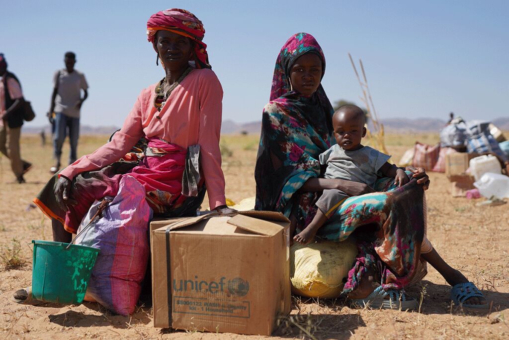 Naiset istuvat avustuslaatikon päällä.