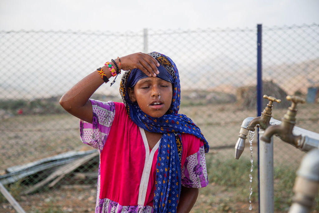 Lapsi kastelee kasvojaan vedellä.