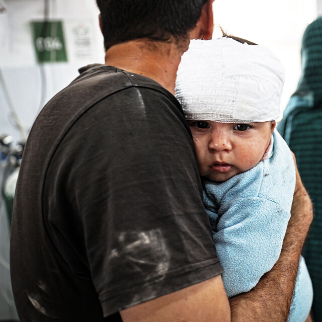 Vauva side päässä aikuisen sylissä.