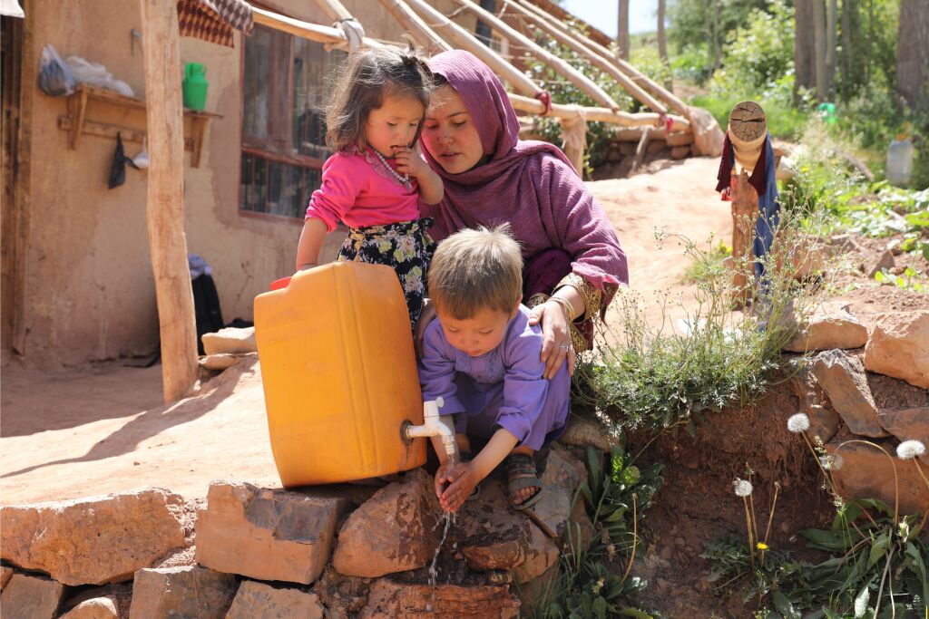 Äiti ja lapset pesevät käsiä kanisterin avulla.