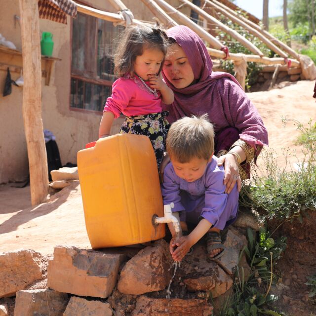 Äiti ja lapset pesevät käsiä kanisterin avulla.