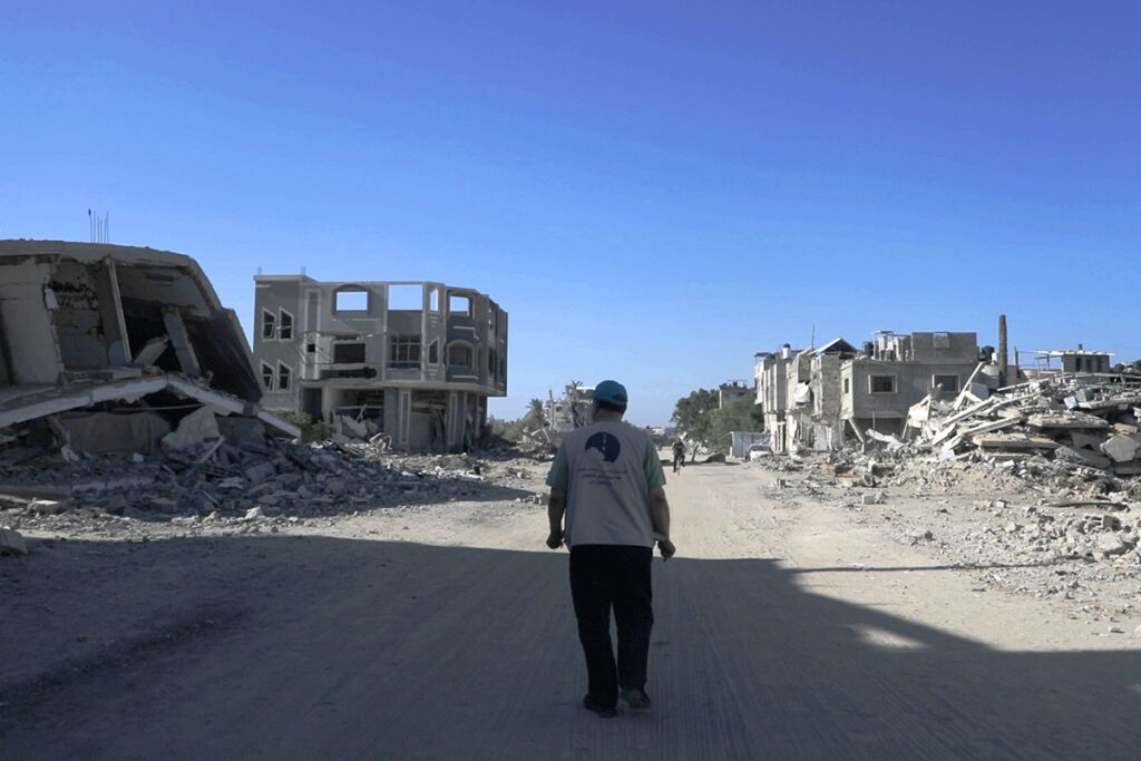 Mies kävelee tiellä raunioiden keskellä.