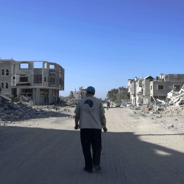 Mies kävelee tiellä raunioiden keskellä.