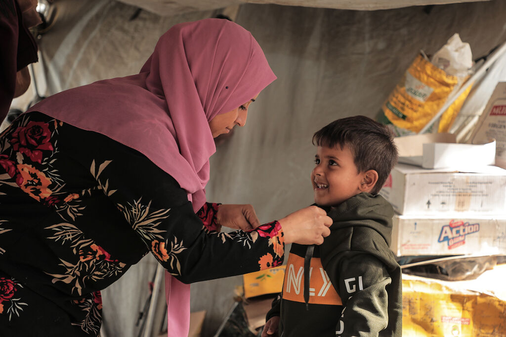 Aikuinen auttaa lapselle takkia.