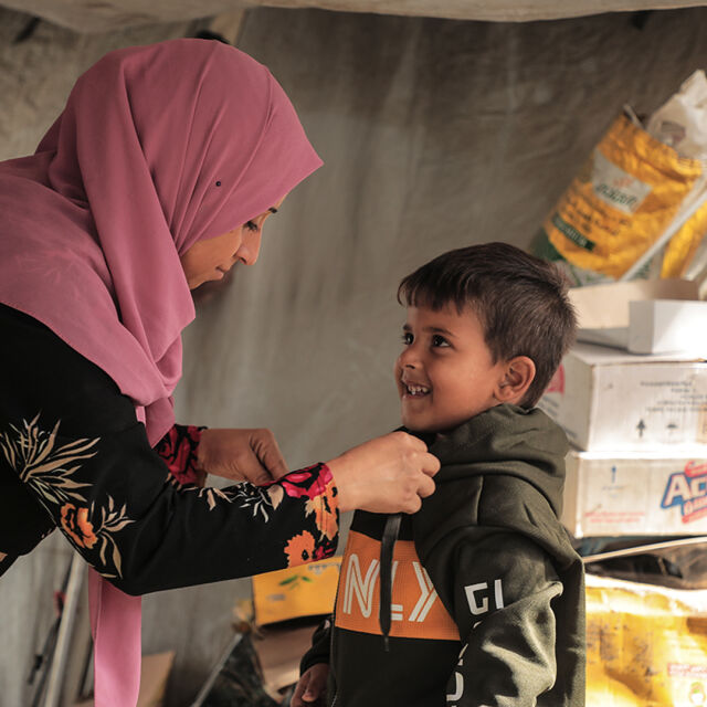 Aikuinen auttaa lapselle takkia.