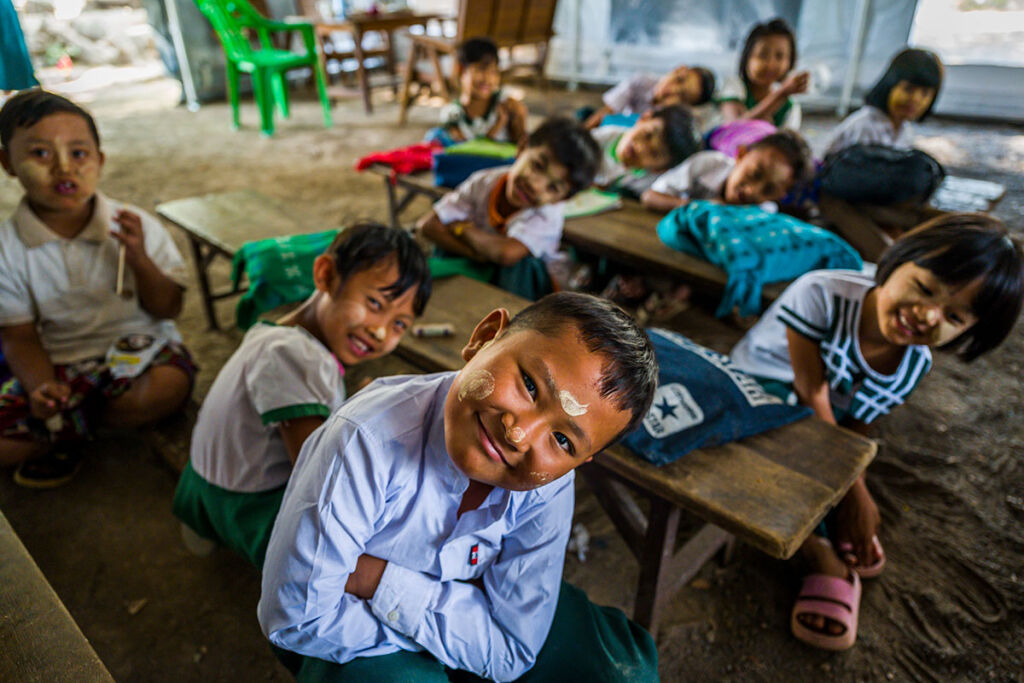 Lapset istuvat pöydän ääressä ja katsovat kameraan.