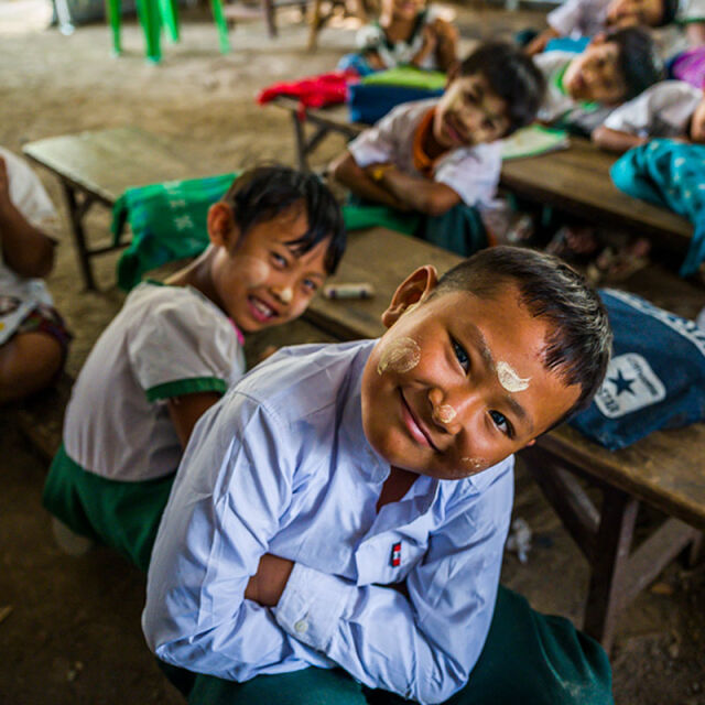 Lapset istuvat pöydän ääressä ja katsovat kameraan.