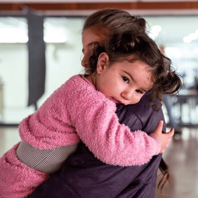 Pinkkiin asuun pukeutunut lapsi halaa aikuista.