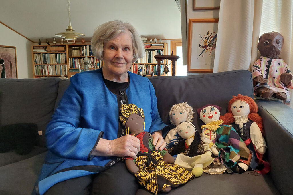 Elisabeth Rehn istuu sohvalla UNICEF-nukkejen kanssa.