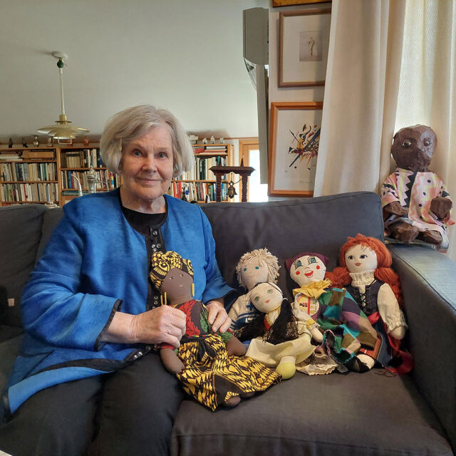 Elisabeth Rehn istuu sohvalla UNICEF-nukkejen kanssa.