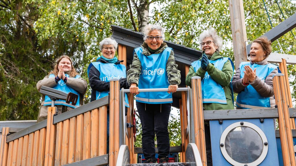 Iloisia UNICEF-vapaaehtoisia leikkitelineessä.