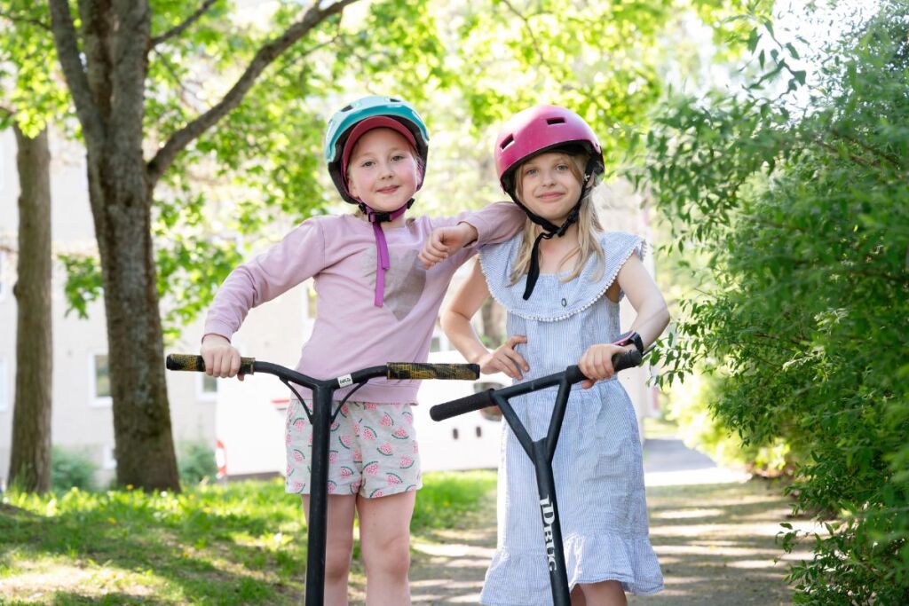 Two children with helmets and scooters.