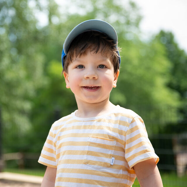Leikki-ikänen lapsi lippalakissa katsoo kameraan.