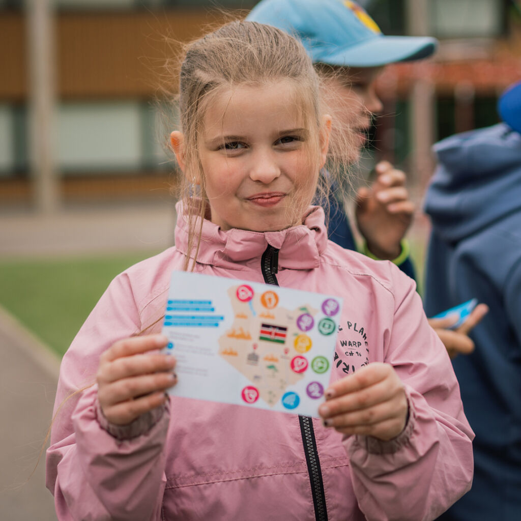 Lapsi esittelee UNICEF-kävelyn passia.