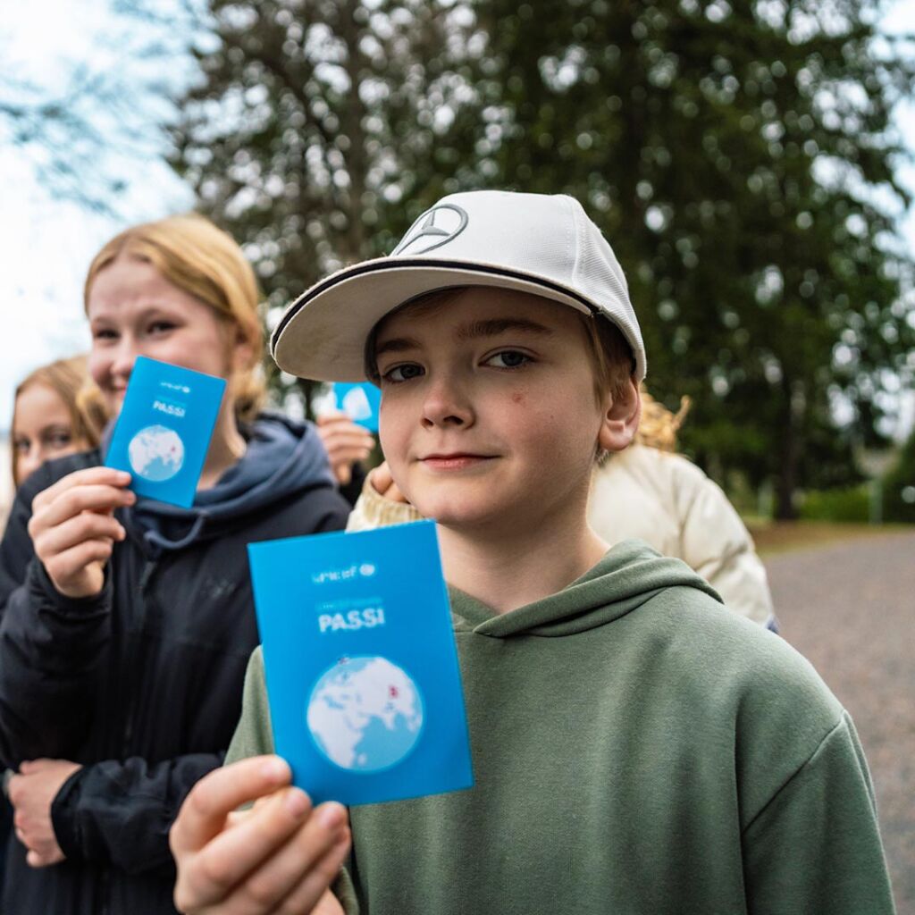 Lapsi esittelee UNICEF-kävelyn passia.