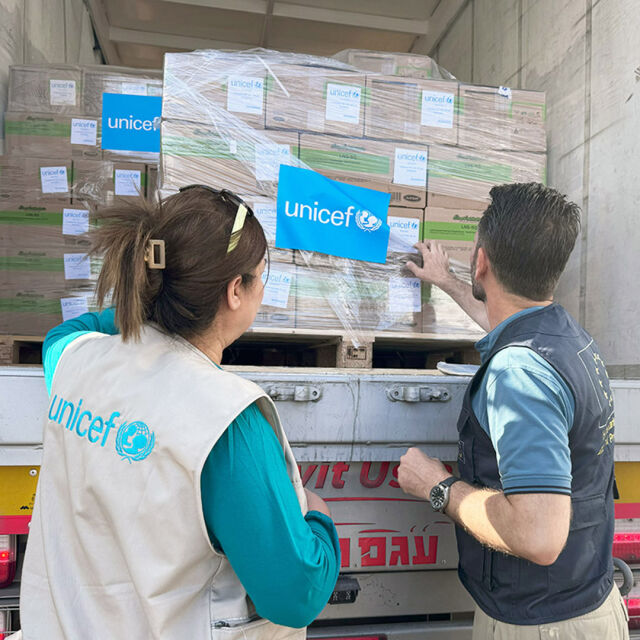 Kaksi ihmistä tutkii rekassa olevia laatikoita. Toisella on UNICEFin liivi. 