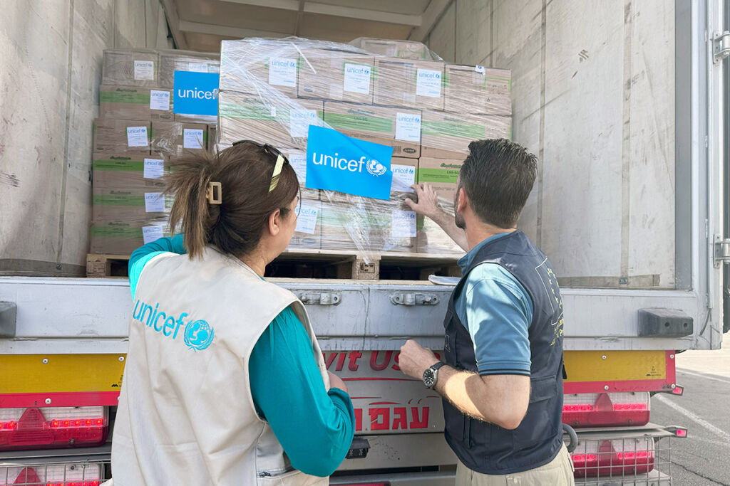 Kaksi ihmistä tutkii rekassa olevia laatikoita. Toisella on UNICEFin liivi. 