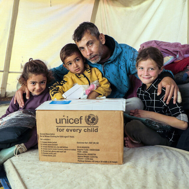 Lapsia ja yksi aikuinen UNICEF-avustuslaatikon äärellä Gazassa.