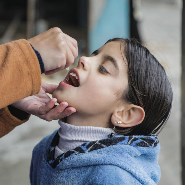 Lapsi saa poliorokotteen UNICEFin työntekijältä.
