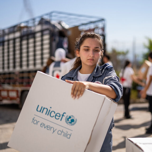 Nuori nainen kantaa laatikkoa, jossa lukee UNICEF. 